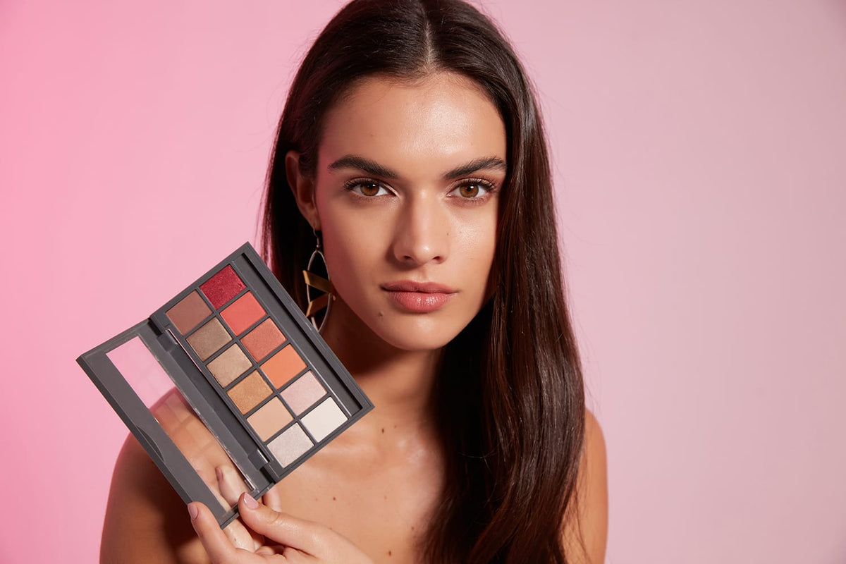 Model holding an Alix Avien eyeshadow palette